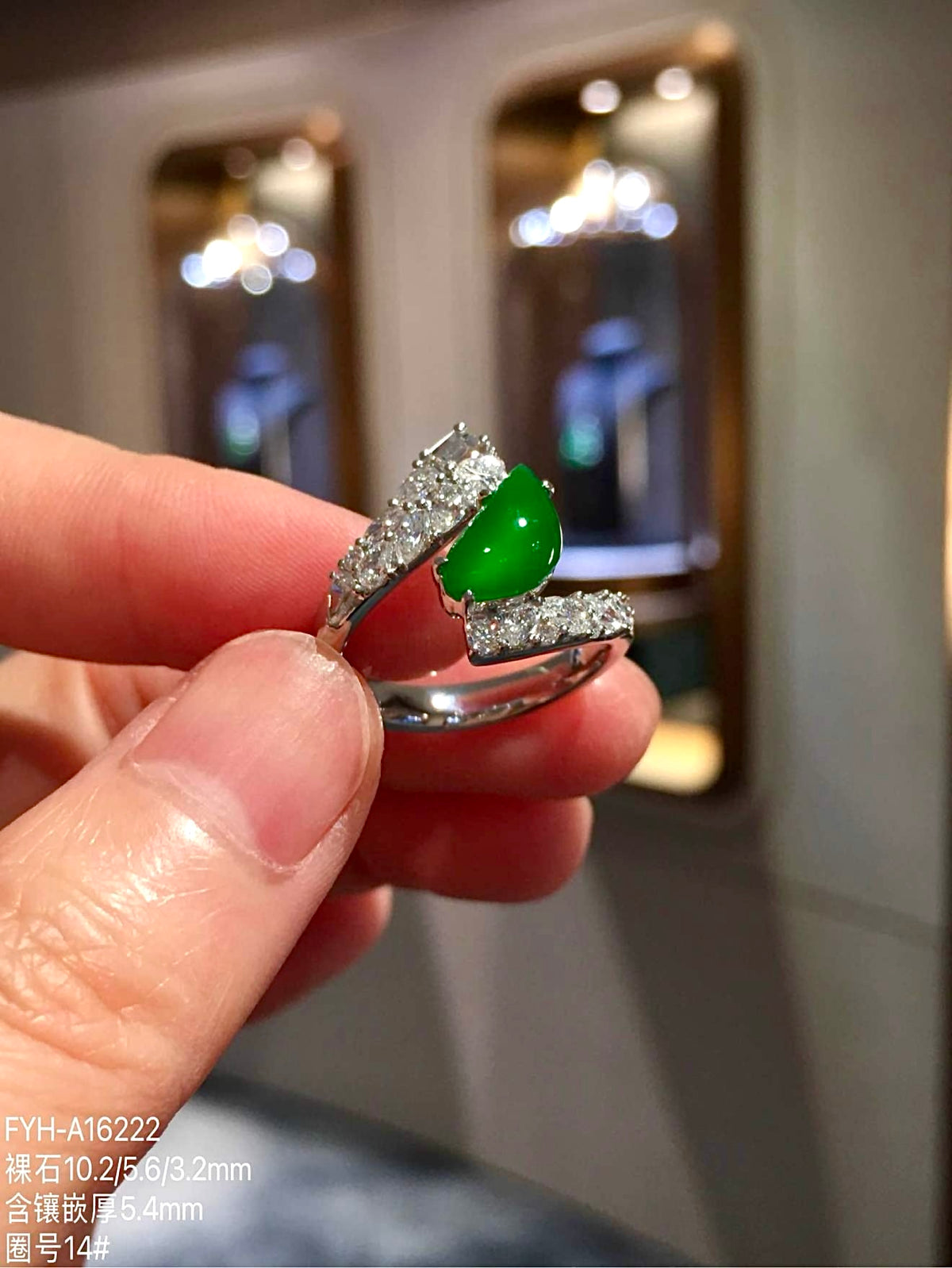 Close-up of green pear-shaped jadeite between diamond-set ring shoulders