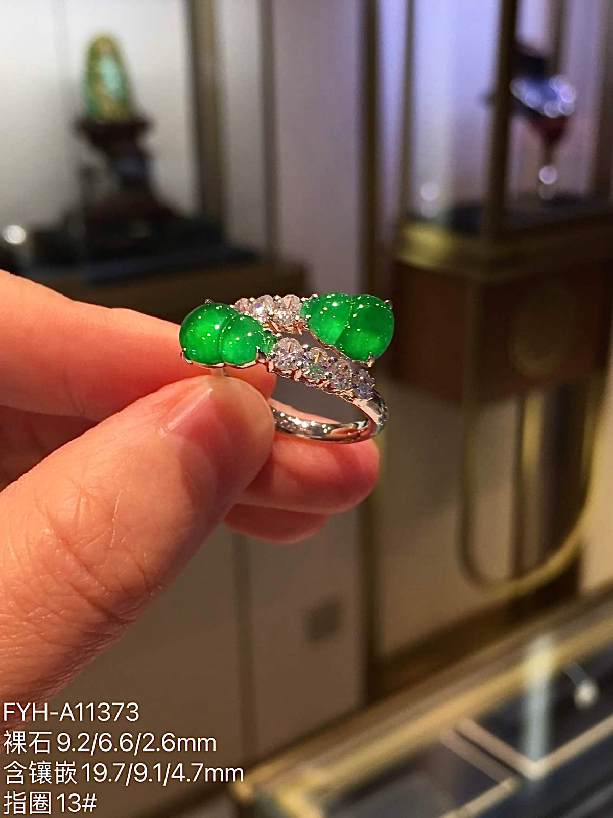 Front view of paired yang green jadeite gourds on an 18K gold and diamond ring