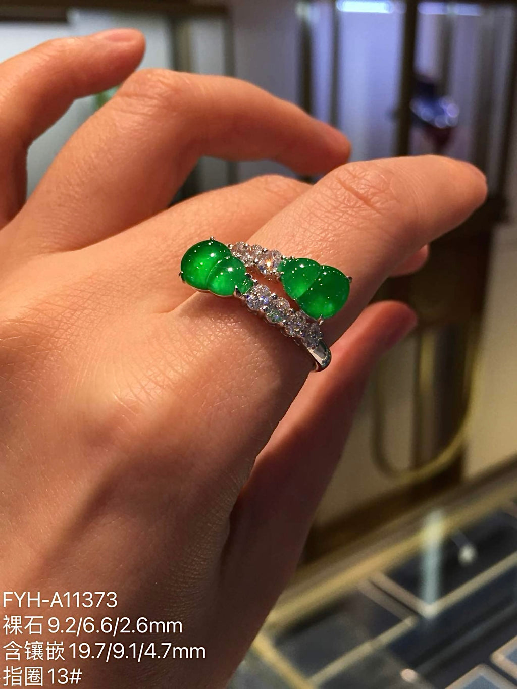 Twin yang green jadeite gourd ring worn on a hand, showing scale and diamond details