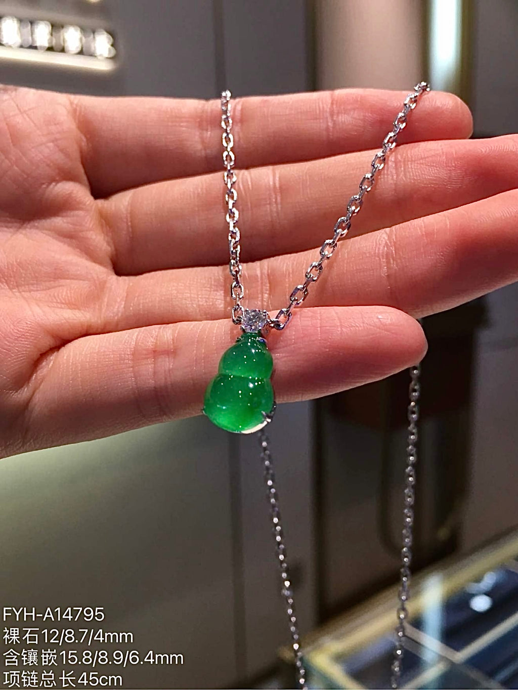 Angled front view of green jadeite gourd necklace and linked chain