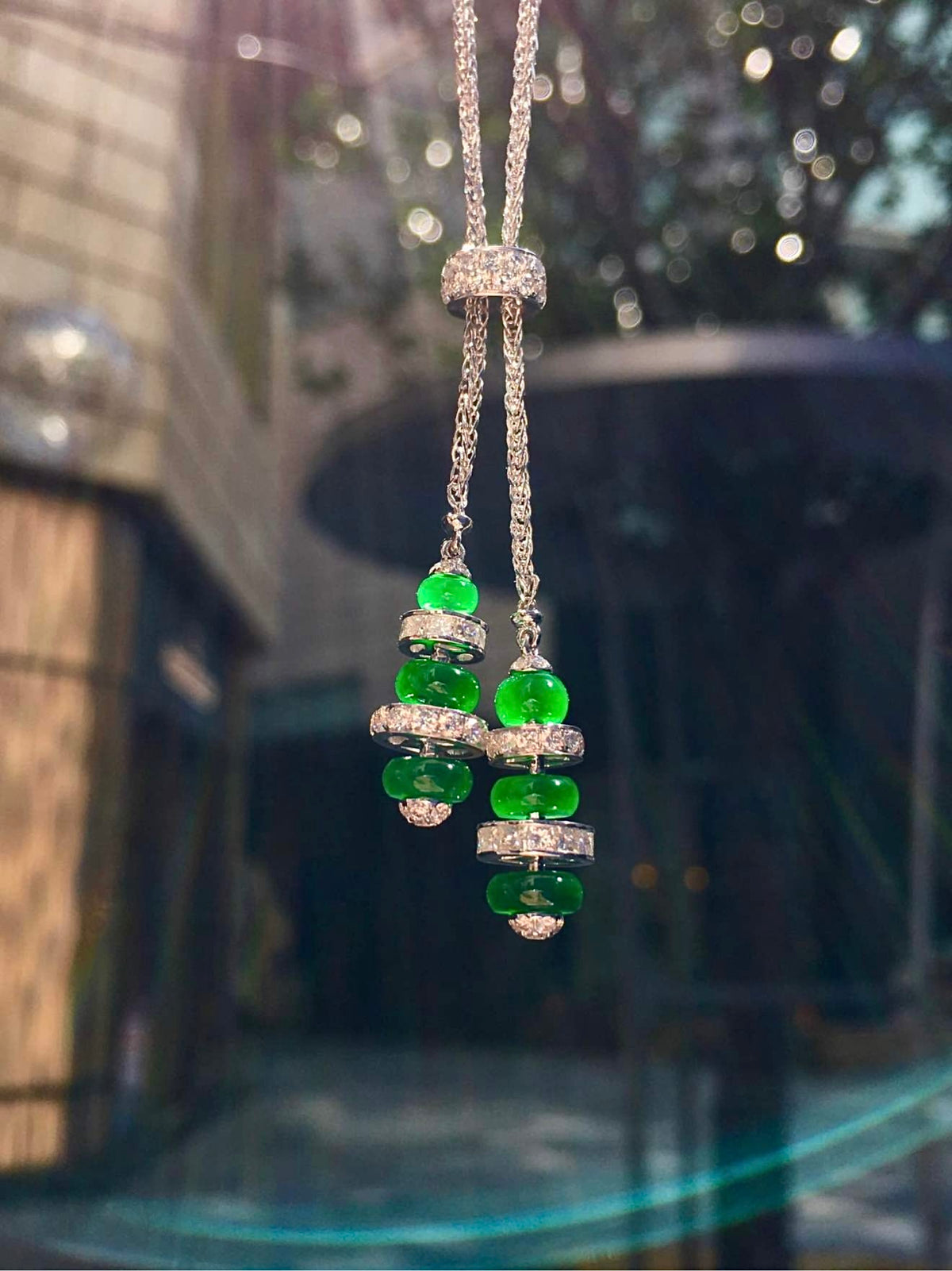 Dark-background view of six green jadeite beads and diamond-set slider