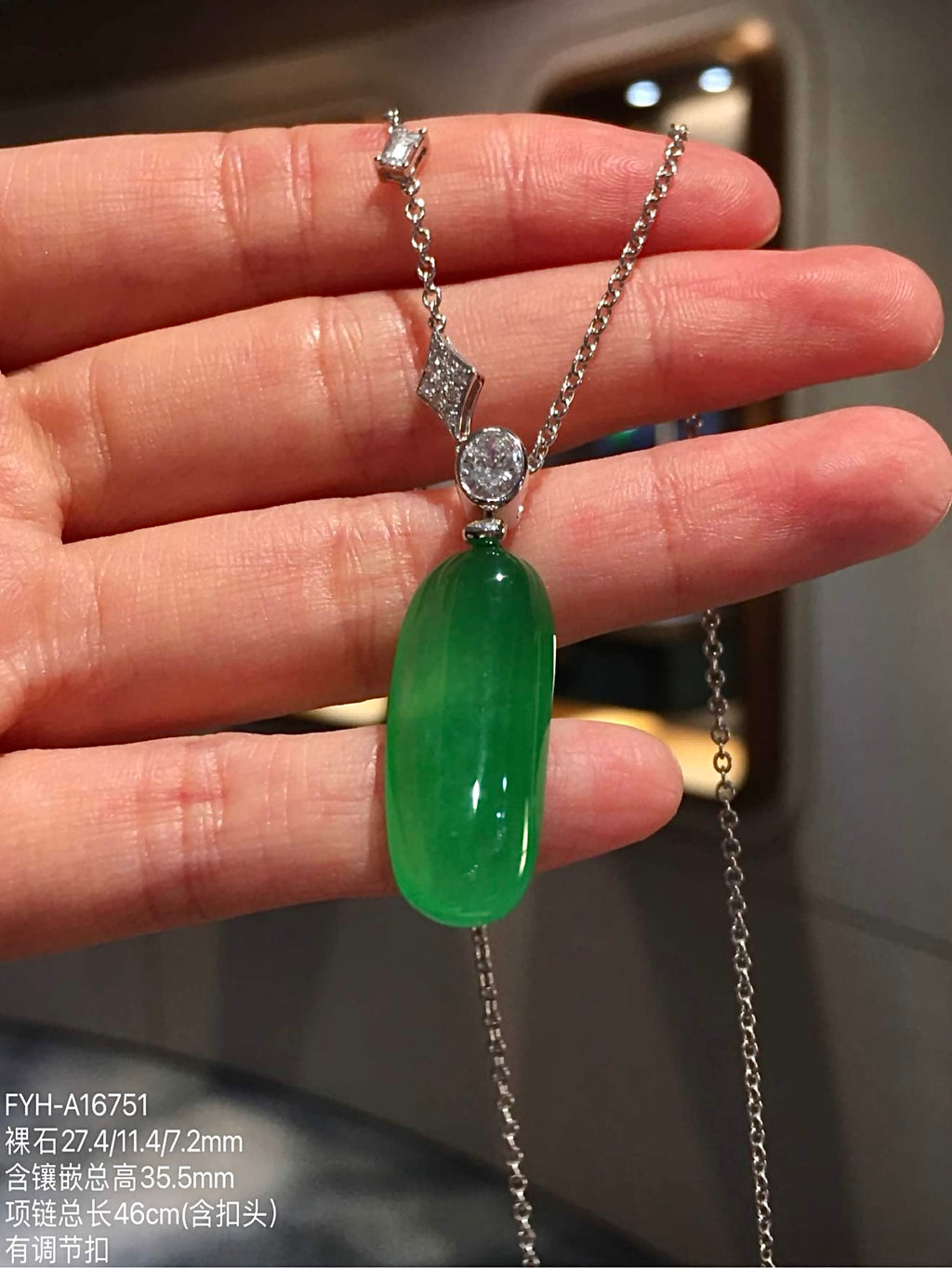 Front detail of green jadeite Fu Gua carving beneath oval diamond accent